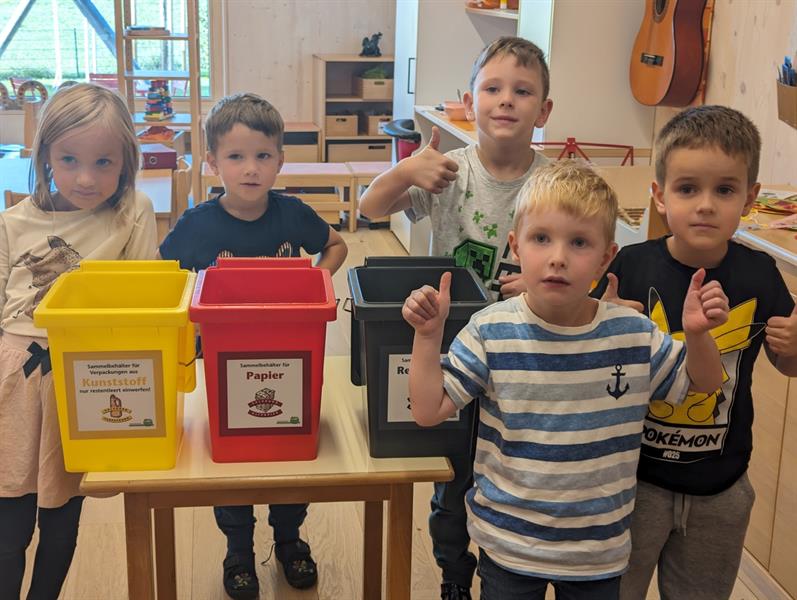 Kinder der orangen Gruppe mit den neuen Müllbehältern